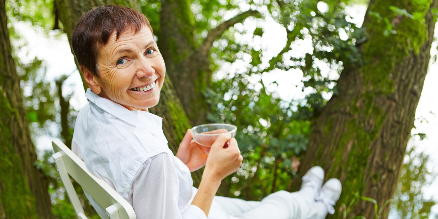 Frau sitzt mit Tee im Grünen 