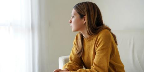 Frau sitzt allein auf dem Sofa und schaut raus