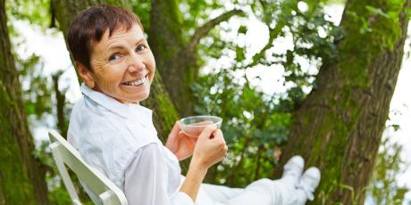 Frau sitzt mit Tee im Grünen 